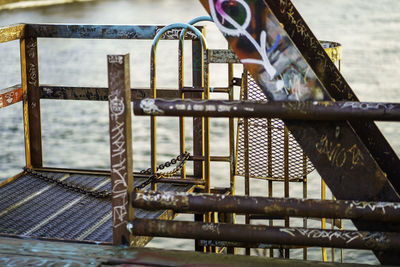 Close-up of metallic railings and top of railway bridge maintenance ladder on river 