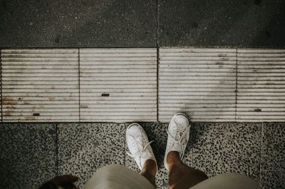 Low section of man standing on tiled floor