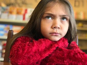 Close-up of girl wearing red warm clothing on chair