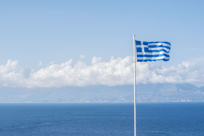 Scenic view of sea against sky and greek flag 