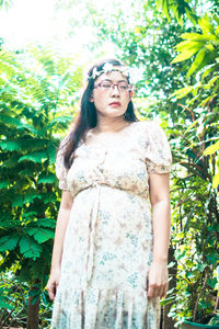 Portrait of a beautiful young woman standing against plants