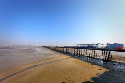 Bridge over sea against clear blue sky