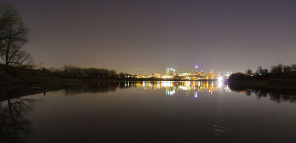 River by illuminated trees against sky at night