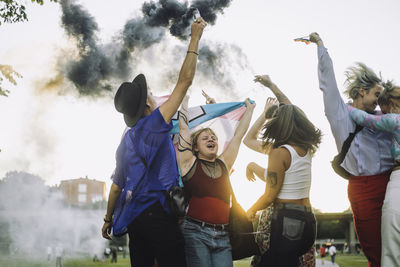 Happy friends with distress flare enjoying lgbtqia rights parade