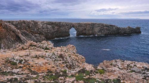 Rock formations by sea against sky