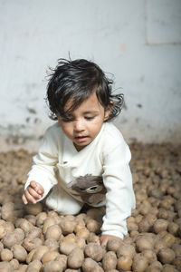 A cute little boy, sitting in a pile of potatoes, playing with potatoes. close up.
