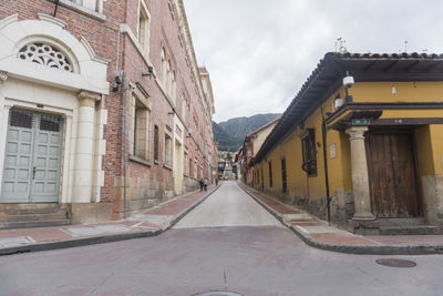 Empty road amidst buildings against sky