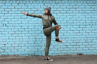 Full length of young woman standing against wall