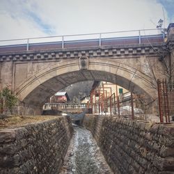 Bridge over river in city against sky