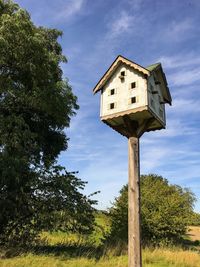 Low angle view of wooden post on field against sky