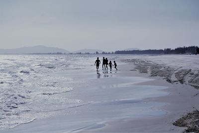 People on snow covered land against sky