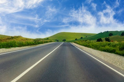 Road amidst green landscape against sky