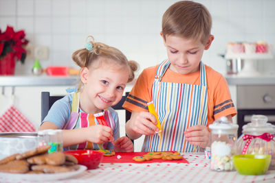 Portrait of cute girl and boy preparing food at kitchen