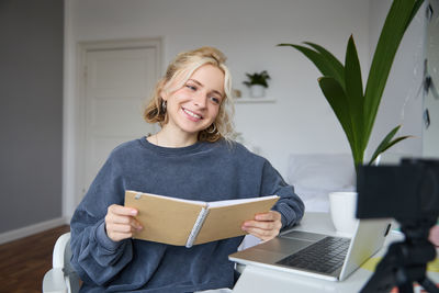 Portrait of young woman using laptop at home