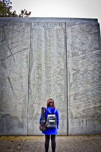 Full length of woman standing against wall