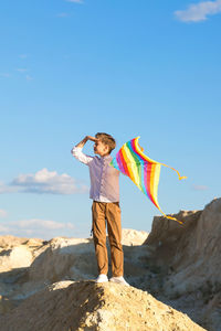 Rear view of woman standing on rock against sky