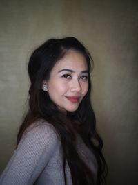 Portrait of smiling young woman against wall