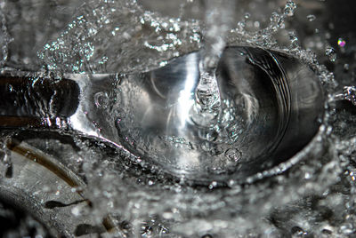 Close-up of water splashing off metal spoon 