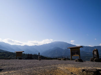 Built structure on field by mountains against blue sky