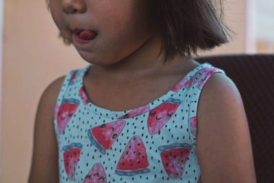 Midsection of girl sticking out tongue