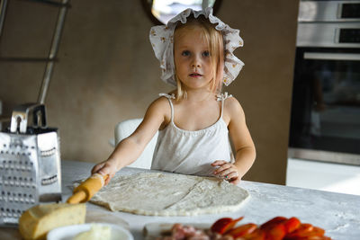 Little girl cooking pizza in the kitchen