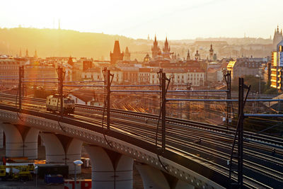 Railroad tracks on bridge in city during sunset