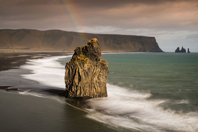 Rock formation in sea against sky