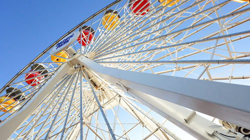 Low angle view of ferris wheel against clear blue sky