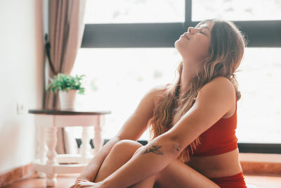 Side view of young woman sitting at home