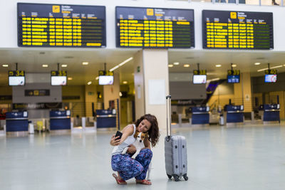 Woman with dog taking selfie at airport