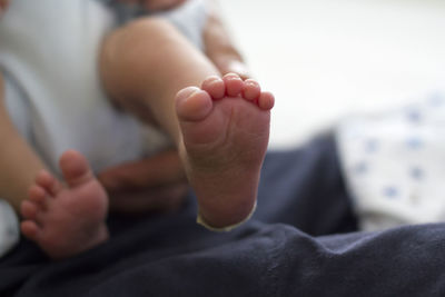 Low section of baby lying on bed