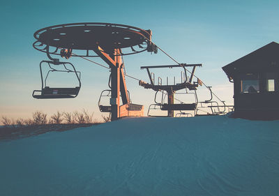 Ski lift on snowy landscape against clear sky