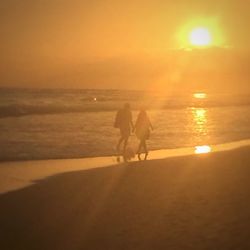 People on beach against sky during sunset