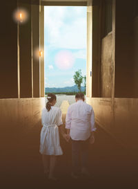 A couple walks hand in hand in a tunnel with light bulbs on the side of the road, 