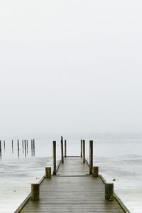 Wooden pier over sea against sky