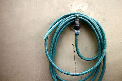 Close-up of blue pipe hanging against wall