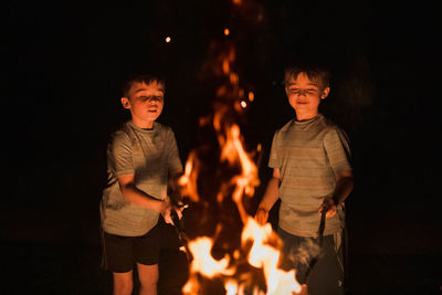 Full length of boy standing against fire at night