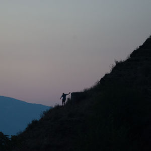 Silhouette man standing on mountain against clear sky