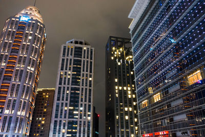 Low angle view of illuminated buildings against sky at night