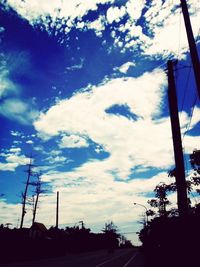 Low angle view of trees against cloudy sky