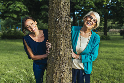 Portrait of a smiling young woman standing on tree trunk