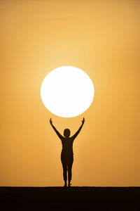 Silhouette man standing in front of orange sky