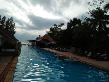 View of swimming pool by canal against sky