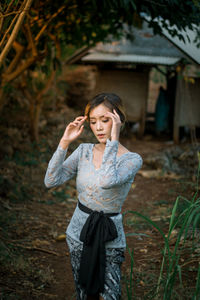 Young woman looking away while standing on field