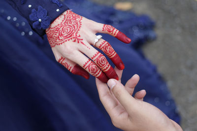 Cropped hand of man holding woman hand with tattoo