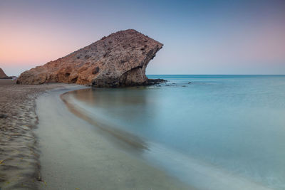 Scenic view of rocks on beach against clear sky