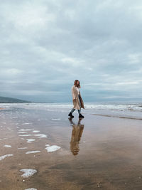 Woman standing at beach against sky and sea