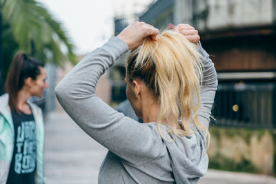 Blonde woman runner tying her hair in a ponytail before training