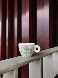 Close-up of coffee cup on railing