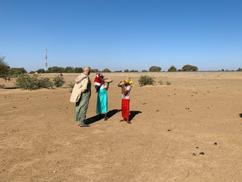 People walking in desert against clear sky